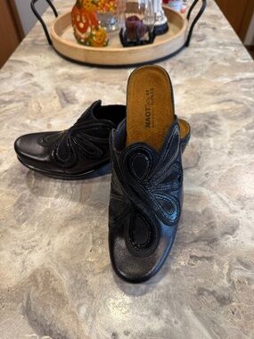 Naot Adore mule clogs in black leather with an intricate floral cut out